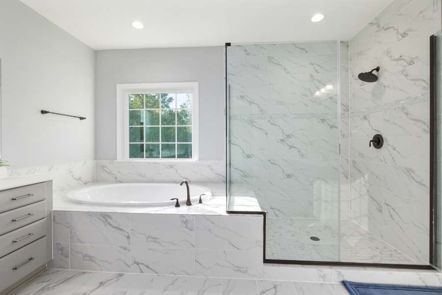 Une élégante salle de bain moderne équipée d'une paroi de douche en verre trempé et d'une baignoire encastrée.