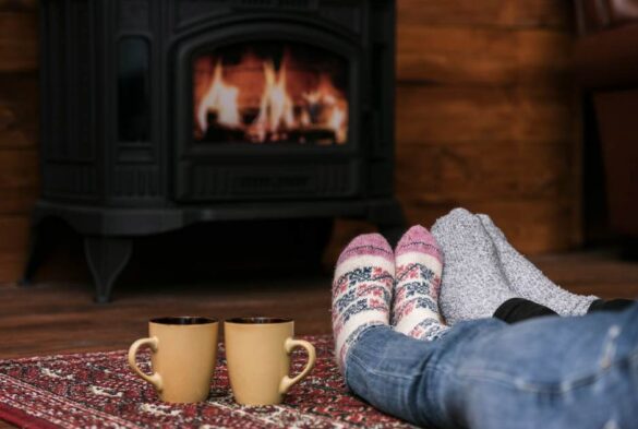 Personnes en chaussettes chaudes devant un poêle à bois allumé pour illustrer l'importance d'améliorer tirage conduit chauffage bois.