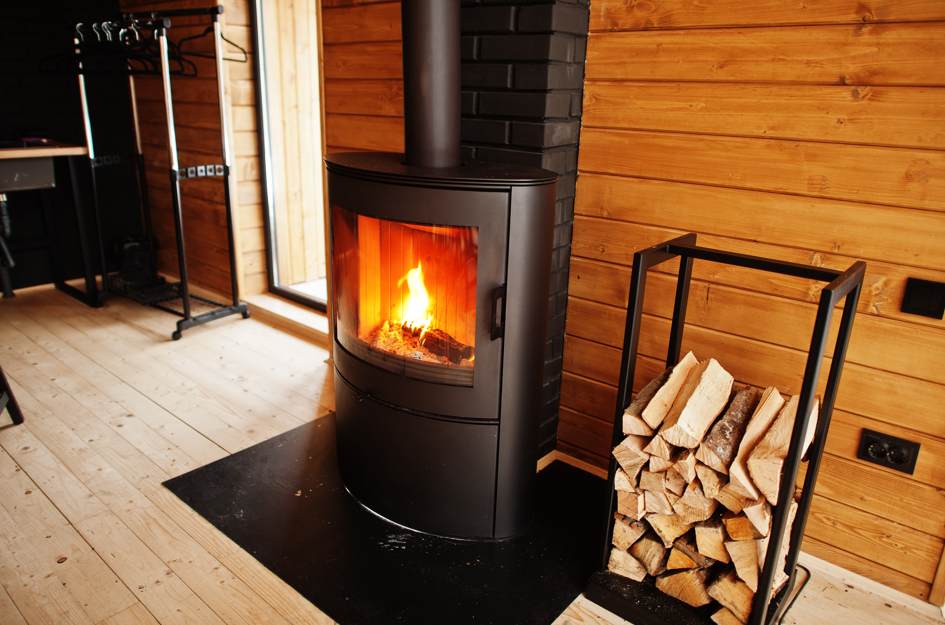 Poêle à bois moderne avec conduit d'évacuation noir et flammes vives, illustrant l'importance d'améliorer tirage conduit chauffage bois.
